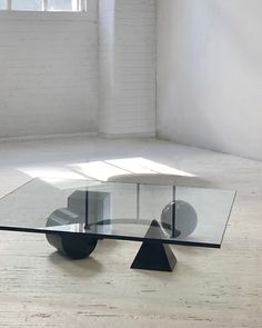 a glass coffee table with wheels on the bottom in an empty room by a window