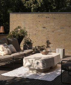 an outdoor living area with couches, tables and potted plants