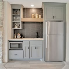 a kitchen with gray cabinets and white tile flooring is shown in this image, there are shelves above the refrigerator