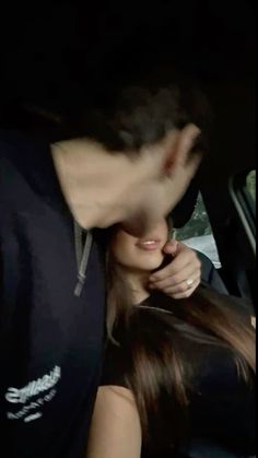 a man and woman kissing in the back seat of a car