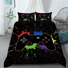 a bed covered in a black comforter with colorful paint splatters on it