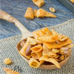 a wooden bowl filled with cheetos sitting on top of a blue table cloth