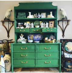 a green china cabinet with plates and vases on it's shelf next to other antiques