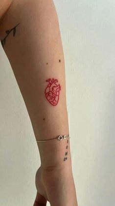 a woman's arm with a red heart tattoo on the left side of her arm