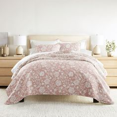 a bed with a pink comforter and pillows