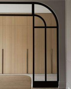 an arched doorway leads into a bedroom with wooden walls and floor to ceiling closets