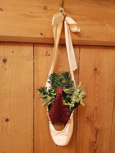 a christmas wreath hanging on the side of a wooden wall with greenery and pine cones