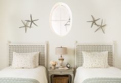 two twin beds in a white bedroom with starfish decorations on the wall above them