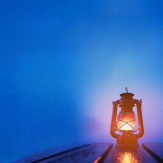 a lantern sitting on top of a wooden table next to a blue sky in the background