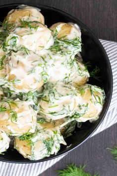 a black bowl filled with potato salad on top of a white and gray table cloth