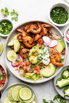 a plate with shrimp, avocado, cilantro, and limes