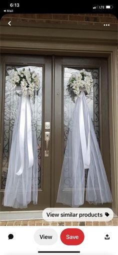 two doors decorated with white flowers and tulle bowes, one door is closed