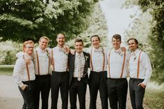 a group of men standing next to each other in front of trees and dirt road