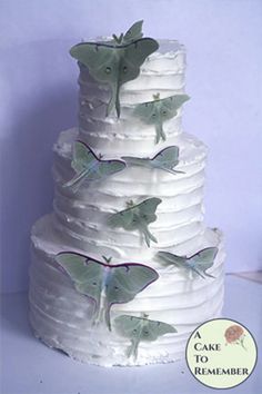 a large white cake with butterflies on it's tiers and the words, a cake to remember