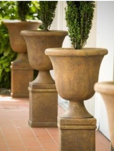 three large planters are lined up on the sidewalk