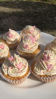 cupcakes with white frosting and sprinkles are arranged on a plate