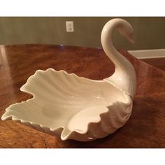 a white swan shaped bowl sitting on top of a wooden table