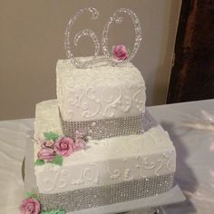 two tiered wedding cake with flowers and the number 60 on top is decorated in white frosting