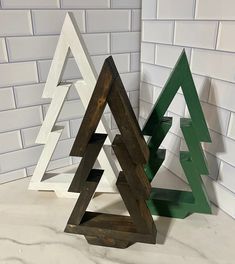 three wooden christmas trees sitting next to each other on top of a white tile floor