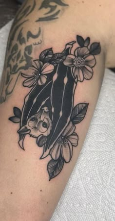 a black and white photo of a tattoo on someone's arm with flowers around it