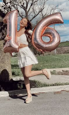 a woman is holding some large balloons in the shape of numbers 6, 6, and 6