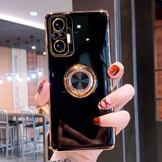 a woman holding up a black phone case with gold ring on it's side