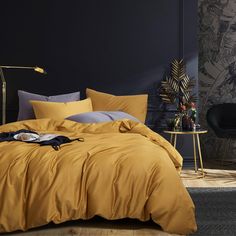 a bed with yellow sheets and pillows in a dark room next to a black wall