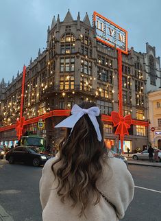 a woman standing in front of a large building with lights on it's sides