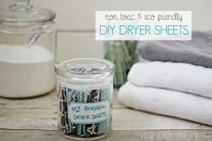 a glass jar filled with dryer sheets sitting on top of a table next to towels