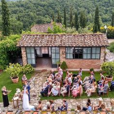 a group of people sitting in chairs on top of a lush green field next to a building