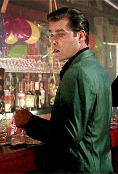 a man standing in front of a bar filled with drinks