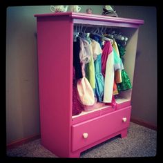 a pink armoire with clothes hanging on it