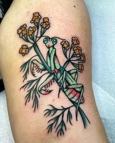 a tattoo on the leg of a woman with flowers and a praying mantissa