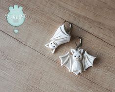 two white ceramic bats are on a wooden table next to a rubber keychain