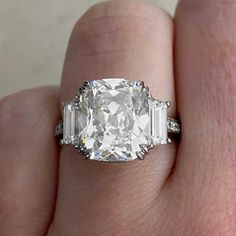 a woman's hand holding an oval and baguette diamond ring