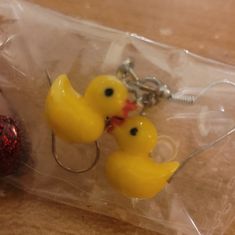 two yellow rubber ducks sitting on top of a plastic bag next to a fishing hook