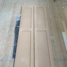 two wooden doors sitting on top of a floor next to a piece of cardboard and some other items