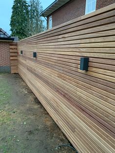 a wooden fence with two black knobs on it's sides and a brick house in the background