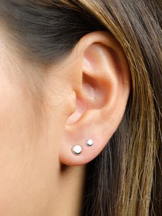 a close up of a woman's ear with two small studs on it