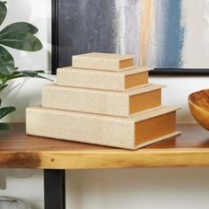 a stack of books sitting on top of a wooden table next to a bowl and plant