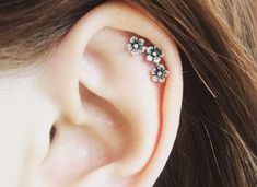 a close up of a person's ear with three flowers on the top of it