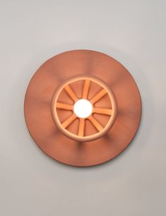 a circular light fixture mounted on the side of a wall with an orange wheel in front of it