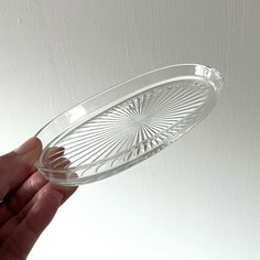 a person holding a clear glass bowl in their hand on a white surface with light coming from the ceiling