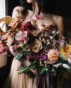 a woman holding a bouquet of flowers in her hands and wearing a dress with an open back