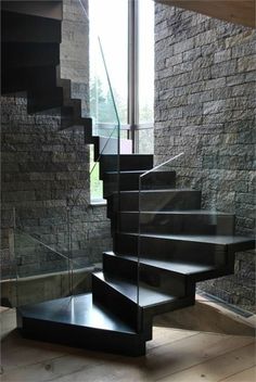 a set of stairs in front of a stone wall and glass door leading up to the second floor