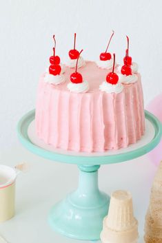 a cake with pink frosting and cherries on top