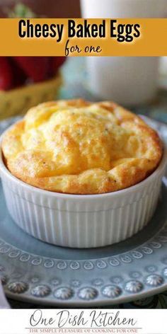 cheesey baked eggs for one in a white dish on a blue plate with strawberries