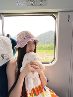 a woman sitting on a train holding a stuffed animal