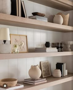 the shelves are filled with books, vases and other decorative items in neutral colors