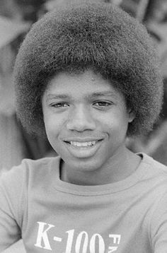 a black and white photo of a boy with an afro